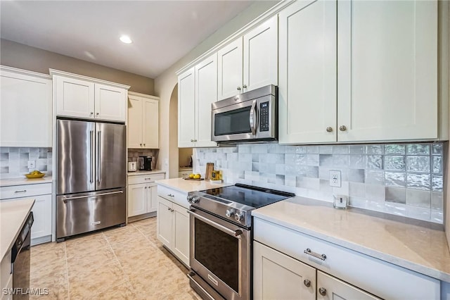 kitchen featuring backsplash, white cabinetry, light tile patterned flooring, and stainless steel appliances