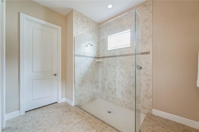 bathroom with tiled shower and tile patterned flooring