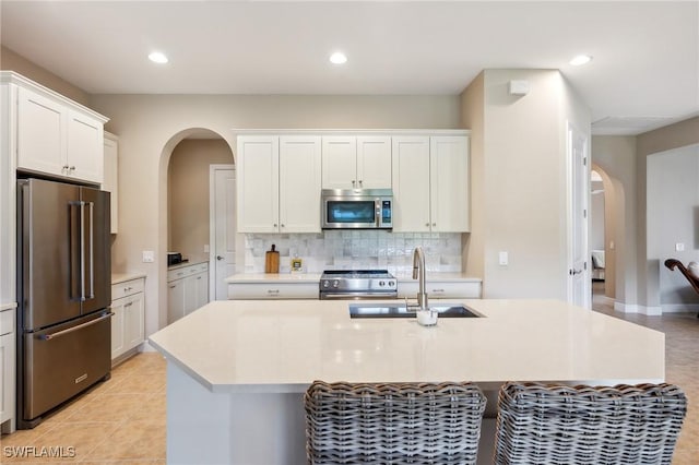 kitchen featuring white cabinets, sink, an island with sink, and high end appliances