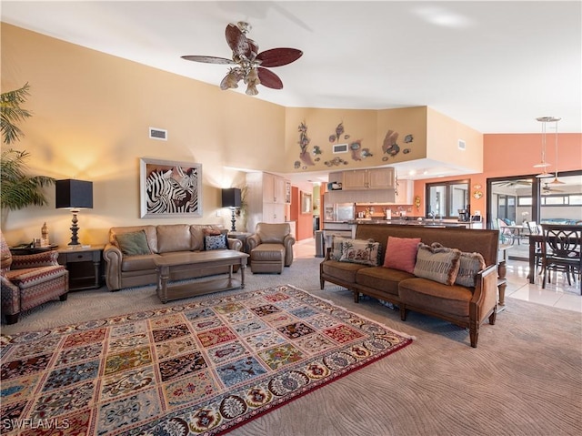 carpeted living room with ceiling fan and high vaulted ceiling