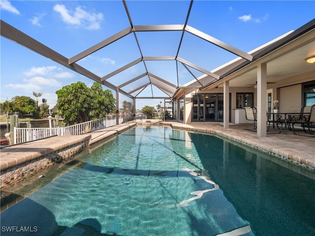 view of swimming pool featuring glass enclosure, a patio area, and ceiling fan