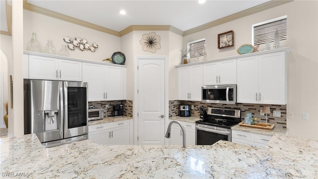 kitchen featuring stainless steel appliances, white cabinetry, tasteful backsplash, and ornamental molding