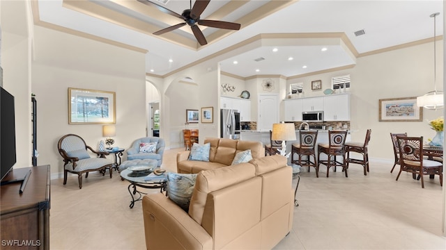 living room featuring crown molding, ceiling fan, a towering ceiling, light tile patterned floors, and a tray ceiling