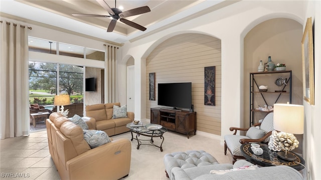 tiled living room featuring a raised ceiling and ceiling fan