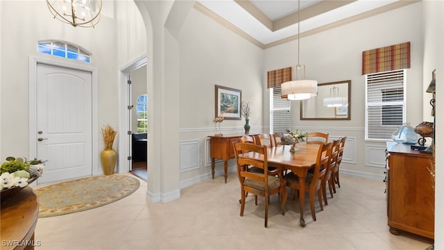 tiled dining area with a chandelier, a high ceiling, and a raised ceiling