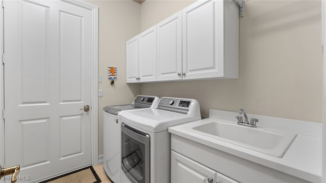 washroom with washer and dryer, cabinets, and sink