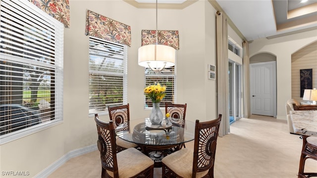 carpeted dining area with crown molding and an inviting chandelier