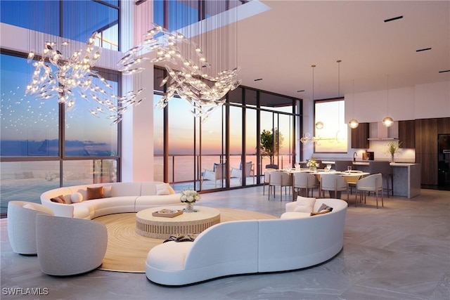 living room with floor to ceiling windows, a towering ceiling, a water view, and a notable chandelier