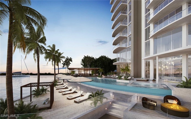 pool at dusk featuring a water view and an outdoor fire pit