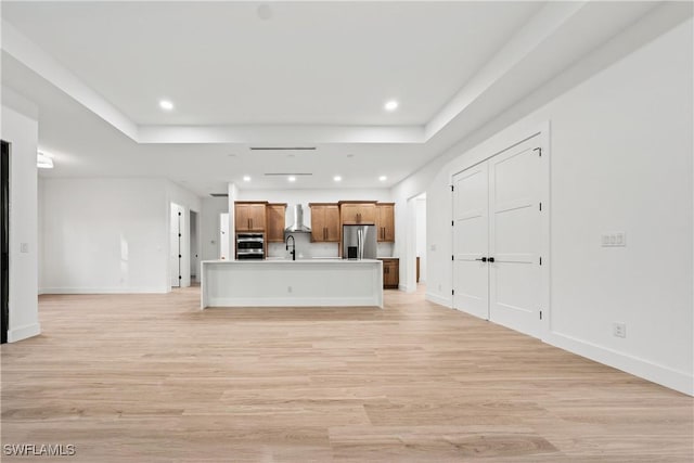 unfurnished living room with light hardwood / wood-style floors, a raised ceiling, and sink