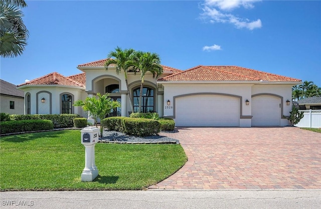 mediterranean / spanish-style house with a garage and a front lawn