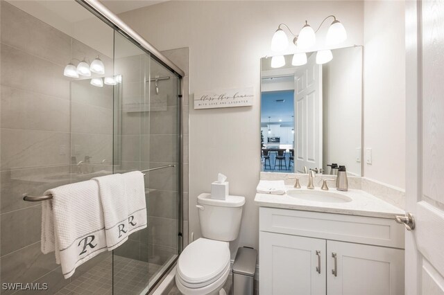 bathroom featuring a shower with door, vanity, and toilet