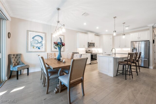 dining room with crown molding, sink, and light wood-type flooring