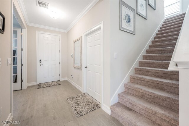 foyer entrance featuring light hardwood / wood-style floors and crown molding