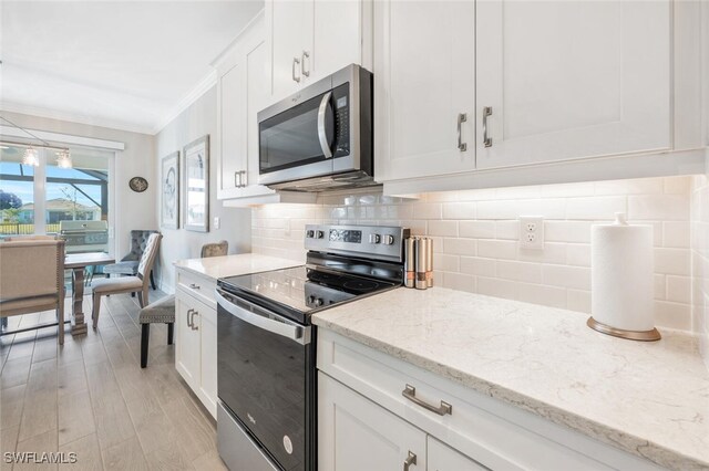 kitchen with light stone countertops, stainless steel appliances, backsplash, white cabinets, and light wood-type flooring