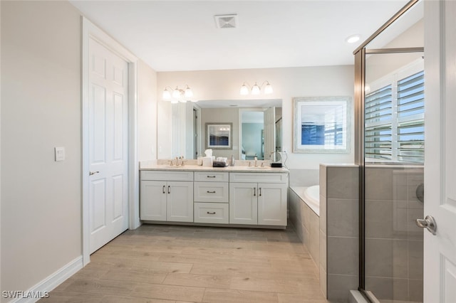 bathroom with hardwood / wood-style floors, vanity, and independent shower and bath