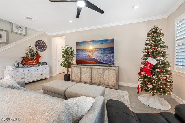 living room featuring light hardwood / wood-style flooring, a wealth of natural light, crown molding, and ceiling fan