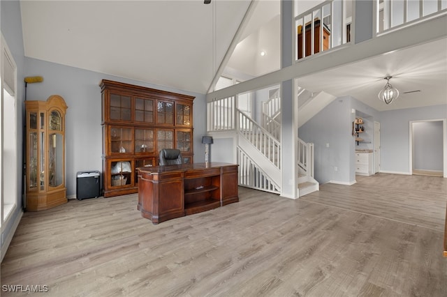 office with high vaulted ceiling, a chandelier, and light wood-type flooring