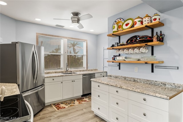 kitchen with white cabinets, sink, light stone countertops, light hardwood / wood-style floors, and stainless steel appliances