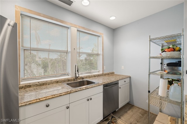 kitchen featuring white cabinets, appliances with stainless steel finishes, light hardwood / wood-style flooring, and sink