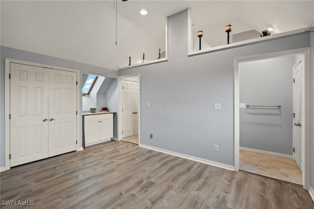 unfurnished bedroom with connected bathroom, high vaulted ceiling, and light hardwood / wood-style floors