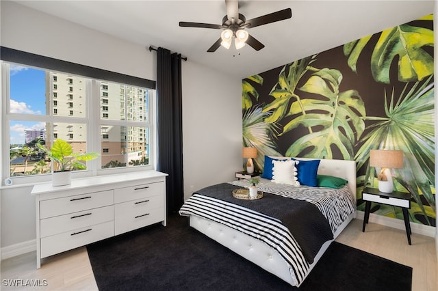 bedroom featuring ceiling fan, light hardwood / wood-style floors, and multiple windows