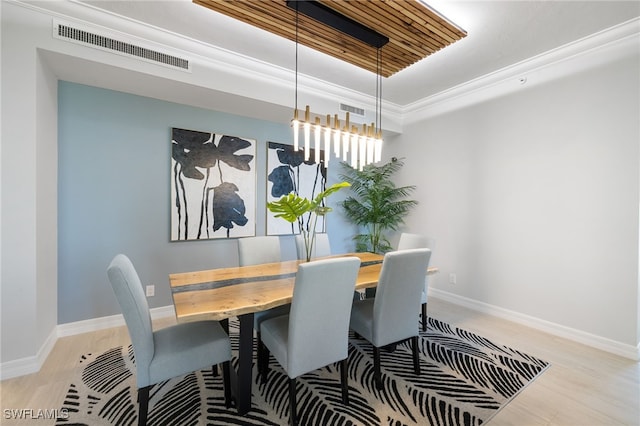 dining space with a raised ceiling, light hardwood / wood-style flooring, a chandelier, and ornamental molding