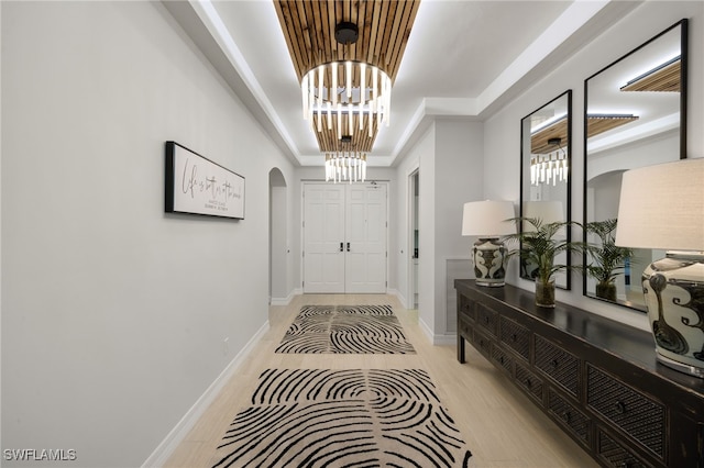 entrance foyer featuring a notable chandelier, light wood-type flooring, and a tray ceiling