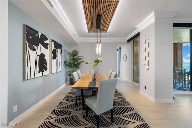 dining space featuring ornamental molding and light hardwood / wood-style flooring