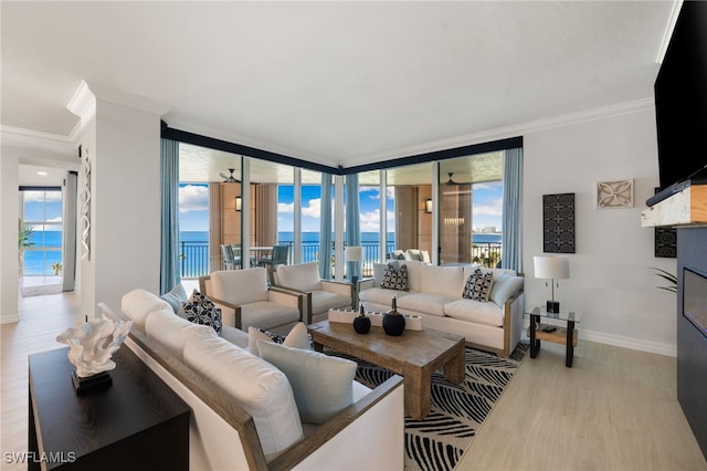 living room featuring light wood-type flooring, a water view, floor to ceiling windows, and crown molding