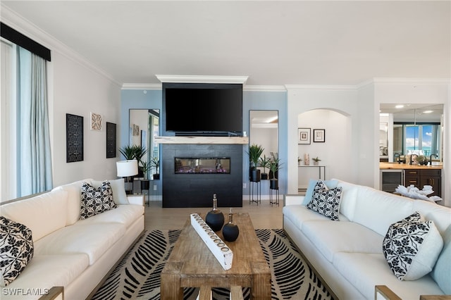 living room with sink, wine cooler, crown molding, a tiled fireplace, and hardwood / wood-style flooring