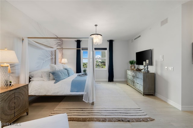 bedroom featuring light wood-type flooring and an inviting chandelier