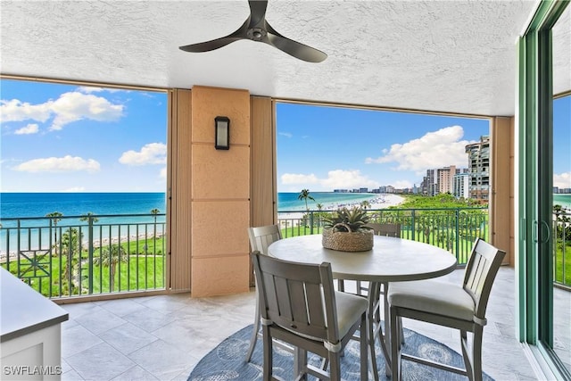 balcony with a beach view, a water view, and ceiling fan