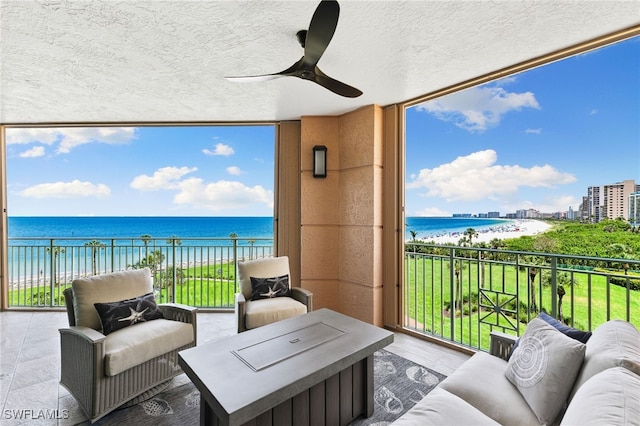 balcony with a beach view, a water view, and ceiling fan