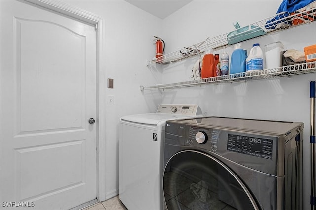 laundry area with washer and clothes dryer and light tile patterned floors