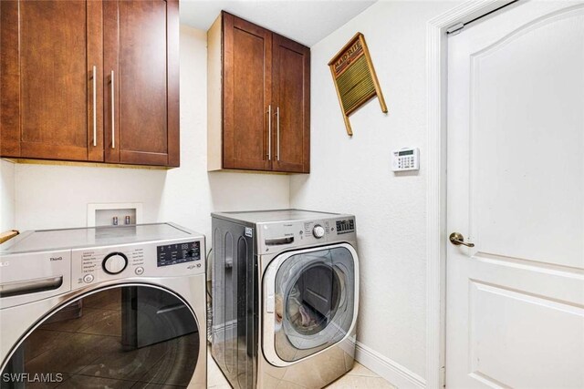 washroom with cabinets, light tile patterned floors, and washing machine and dryer