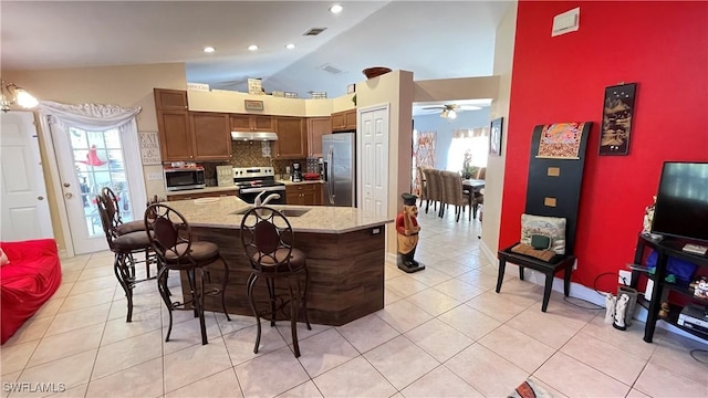 kitchen featuring appliances with stainless steel finishes, a wealth of natural light, a kitchen breakfast bar, and ceiling fan