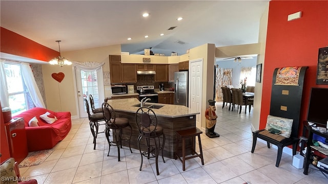 kitchen featuring lofted ceiling, sink, decorative light fixtures, a center island with sink, and appliances with stainless steel finishes