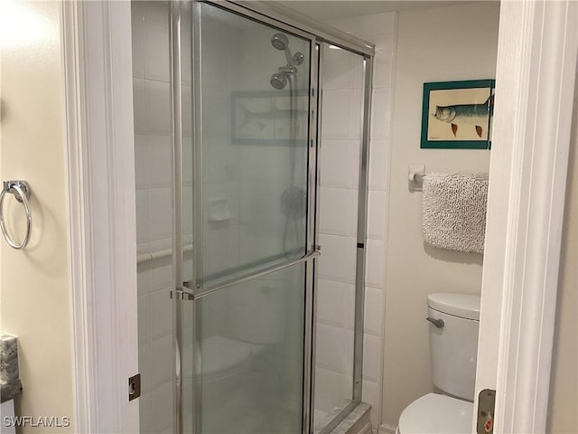 bathroom featuring toilet and a shower with shower door