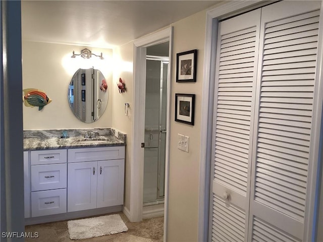 bathroom featuring a shower with door and vanity