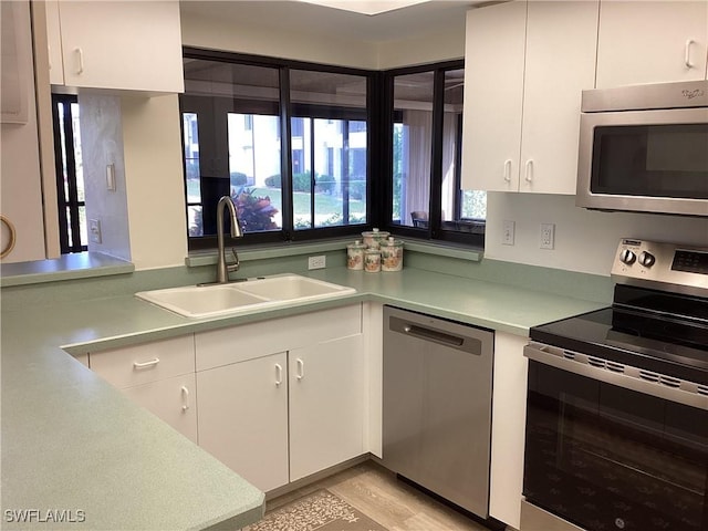 kitchen with sink, white cabinets, stainless steel appliances, and light wood-type flooring