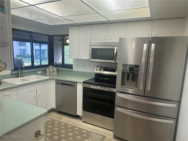 kitchen featuring stainless steel appliances, white cabinetry, light hardwood / wood-style floors, and sink