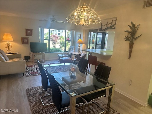 dining space featuring ceiling fan with notable chandelier and hardwood / wood-style flooring