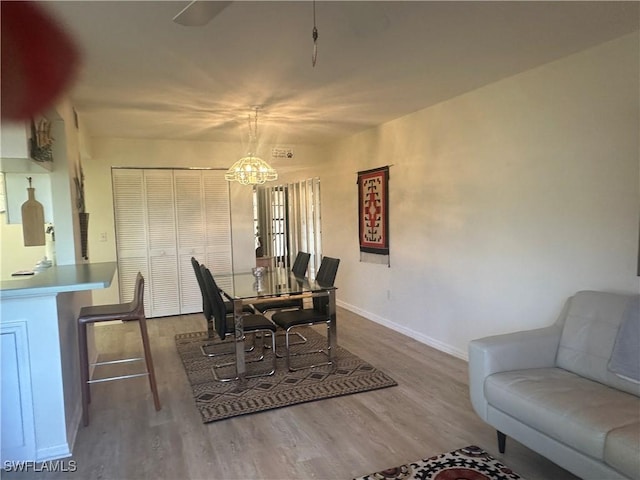 dining area with wood-type flooring and a notable chandelier