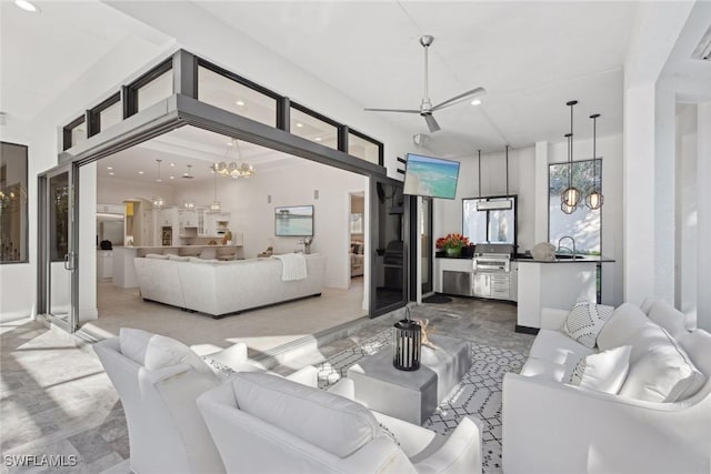 living room with ceiling fan with notable chandelier and sink