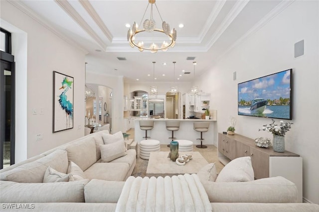 living room featuring a tray ceiling, a chandelier, and ornamental molding