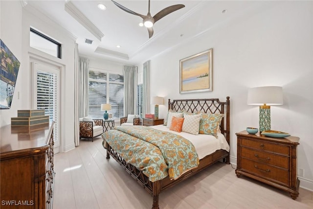 bedroom featuring a tray ceiling, ceiling fan, crown molding, and light hardwood / wood-style floors