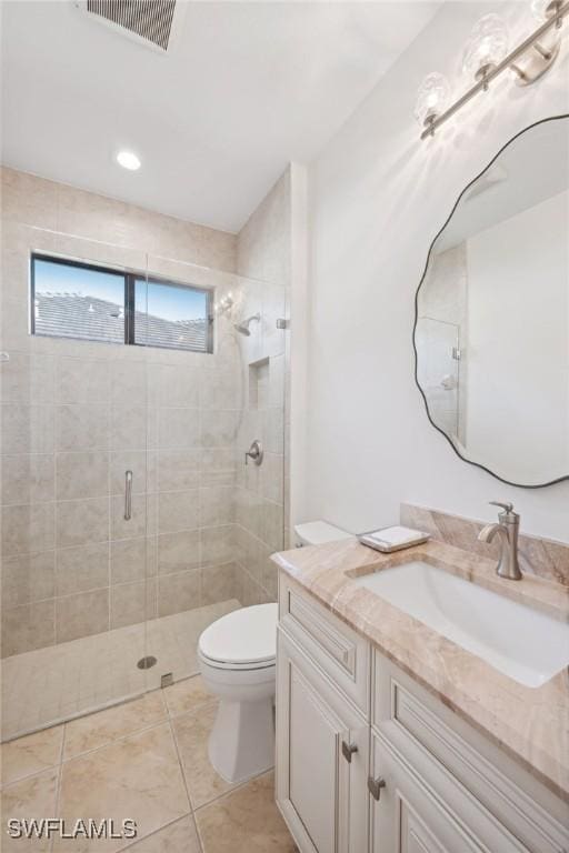 bathroom featuring toilet, vanity, tile patterned floors, and an enclosed shower