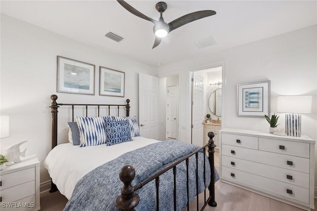 bedroom with ensuite bath, ceiling fan, and light hardwood / wood-style flooring