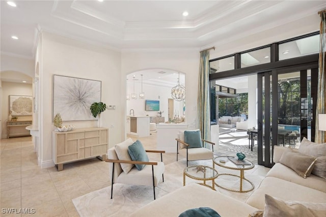 tiled living room with sink, a tray ceiling, crown molding, and a notable chandelier